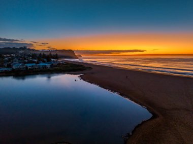 Orta Sahildeki Avoca Sahili, NSW, Avustralya 'daki deniz ve lagünün gündoğumu görüntülerini izliyorum..