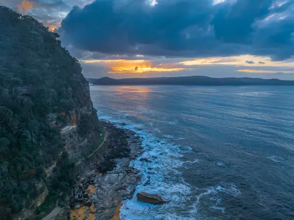 stock image Aerial sunrise at the seaside with a chance of rain amongst the low and medium cloud cover at North Pearl Beach on the Central Coast, NSW, Australia.