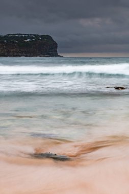 Central Coast, NSW, Avustralya 'daki Macmaster Sahili' nde küçük dalgalarla bulutlu gün doğumu deniz manzarası.