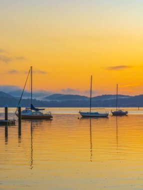 Aerial sunrise waterscape with boats, reflections and some fog around the mountains from Couche Park at Koolewong on the Central Coast, NSW, Australia. clipart