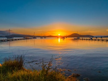 Botlarla, yansımalarla ve dağların etrafındaki hava güneşli su manzarası Orta Sahildeki Couche Park 'tan, NSW, Avustralya' daki Couche Park 'tan..