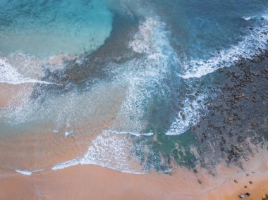 Kumsalda bulutlu bir güneş doğumu manzarası var. Deniz dalgaları, kayalar ve deniz yosunlarıyla dolu. Central Coast, NSW, Avustralya 'daki Macmaster Sahili' nde..