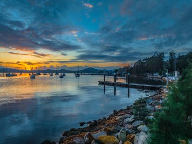 Sunrise and clouds with boats on Brisbane Water at Koolewong and Tascott on the Central Coast, NSW, Australia. clipart