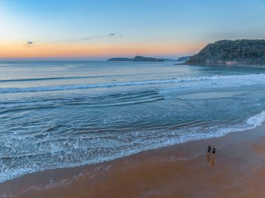 Sonbahar gündoğumu gökyüzünde güzel bulutlar ve nemli kumdaki yansımalarla Orta Sahildeki Umina Sahili, NSW, Avustralya.