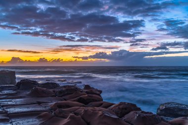 Central Coast, NSW, Avustralya 'daki Kuzey Avoca Kaya Platformu' nda bulutlu ve dalgalı gün doğumu deniz manzarası.