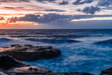 Central Coast, NSW, Avustralya 'daki Kuzey Avoca Kaya Platformu' nda bulutlu ve dalgalı gün doğumu deniz manzarası.