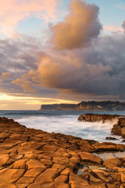 Central Coast, NSW, Avustralya 'daki Kuzey Avoca Kaya Platformu' nda bulutlu ve dalgalı gün doğumu deniz manzarası.