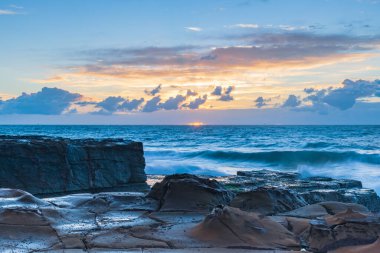 Sunrise seascape with clouds and waves at North Avoca Rock Platform on the Central Coast, NSW, Australia. clipart