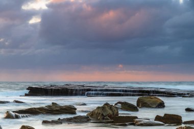 Terrigal, NSW, Avustralya 'daki The Skillion' da sonbahar gündoğumu bulutları ve şelaleleri..