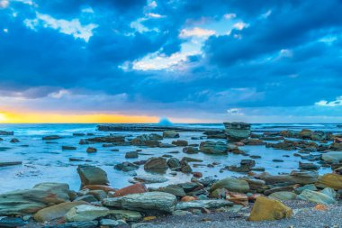 Terrigal, NSW, Avustralya 'daki The Skillion' da sonbahar gündoğumu bulutları ve kayalarla birlikte deniz manzarası.