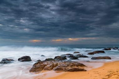 Central Coast, NSW, Avustralya 'daki Killcare Sahili' nde dalgalar ve kayalarla bulutlu bir deniz doğumu..