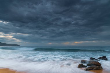 Cloudy sunrise seascape with waves and rocks at Killcare Beach on the Central Coast, NSW, Australia. clipart