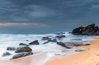 Central Coast, NSW, Avustralya 'daki Killcare Sahili' nde dalgalar ve kayalarla bulutlu bir deniz doğumu..