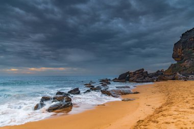 Central Coast, NSW, Avustralya 'daki Killcare Sahili' nde dalgalar ve kayalarla bulutlu bir deniz doğumu..