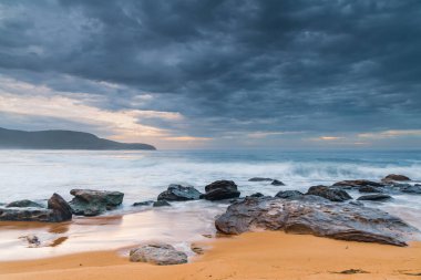 Cloudy sunrise seascape with waves and rocks at Killcare Beach on the Central Coast, NSW, Australia. clipart