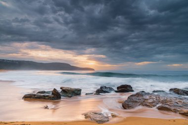 Cloudy sunrise seascape with waves and rocks at Killcare Beach on the Central Coast, NSW, Australia. clipart