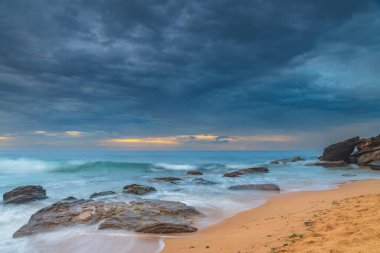 Central Coast, NSW, Avustralya 'daki Killcare Sahili' nde dalgalar ve kayalarla bulutlu bir deniz doğumu..