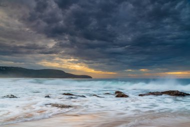 Cloudy sunrise seascape with waves and rocks at Killcare Beach on the Central Coast, NSW, Australia. clipart