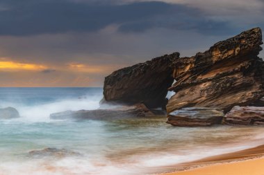 Central Coast, NSW, Avustralya 'daki Killcare Sahili' nde dalgalar ve kayalarla bulutlu bir deniz doğumu..