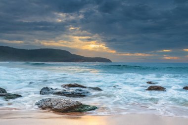 Central Coast, NSW, Avustralya 'daki Killcare Sahili' nde dalgalar ve kayalarla bulutlu bir deniz doğumu..