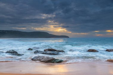 Central Coast, NSW, Avustralya 'daki Killcare Sahili' nde dalgalar ve kayalarla bulutlu bir deniz doğumu..