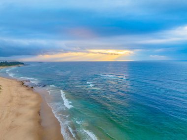 Büyük Newcastle 'daki Swansea Yarımadası' ndaki Caves Beach 'te bulutlu bir gökyüzü ile deniz kenarında gün doğumu. Mağara Sahili, Avustralya 'nın NSW bölgesinin Hunter-Central Coast bölgesinde yer almaktadır..