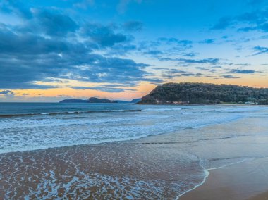 Central Coast, NSW, Avustralya 'daki Umina Sahili' nde alçak bulutlarla sabah güneşinin doğuşu.