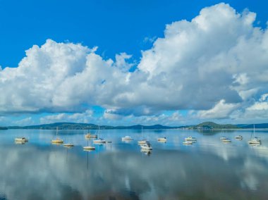 Daytime flight over Brisbane Water with low cloud, reflections and boats at Koolewong and Tascott on the Central Coast, NSW, Australia. clipart