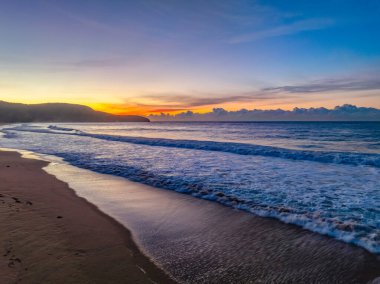 Gündoğumu denizi yumuşak bulutlu ve dalgalı Orta Sahildeki Killcare Sahili, NSW, Avustralya.