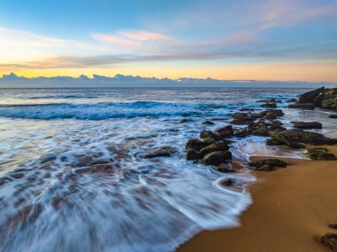 Gündoğumu denizi yumuşak bulutlu ve dalgalı Orta Sahildeki Killcare Sahili, NSW, Avustralya.