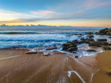 Gündoğumu denizi yumuşak bulutlu ve dalgalı Orta Sahildeki Killcare Sahili, NSW, Avustralya.