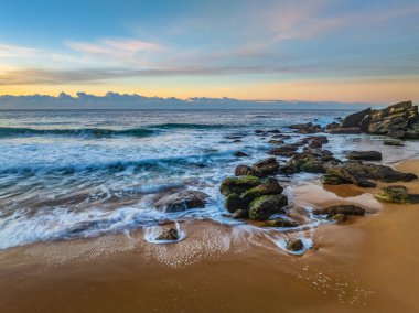 Gündoğumu denizi yumuşak bulutlu ve dalgalı Orta Sahildeki Killcare Sahili, NSW, Avustralya.