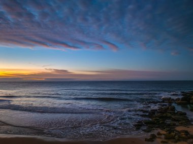 Gündoğumu deniz manzarası. Yüksek ve orta büyüklükteki bulutların karışımı. Killcare Sahili üzerinde güzel bir gökyüzü..