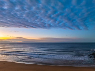 Gündoğumu deniz manzarası. Yüksek ve orta büyüklükteki bulutların karışımı. Killcare Sahili üzerinde güzel bir gökyüzü..