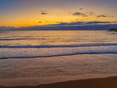 Avustralya 'nın NSW' nin güney kıyısındaki Malua Körfezi 'ne doğru ilerleyen yağmur bulutlarıyla birlikte gün doğumu denizi.