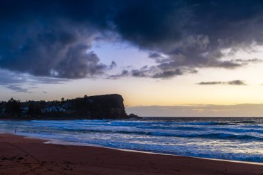Sydney, NSW, Avustralya 'nın kuzey sahillerindeki Avalon' da kayalar ve dalgalarla gün doğumu.