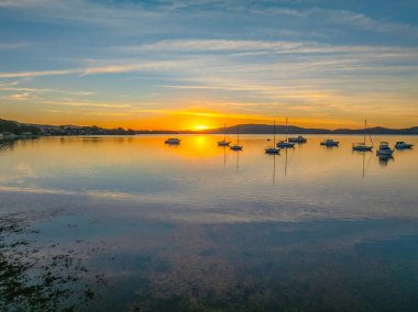 NSW, Avustralya 'nın merkez sahillerinde Brisbane Su ve Koolewong üzerinde bulutlu ve tekneli hava gündoğumu.