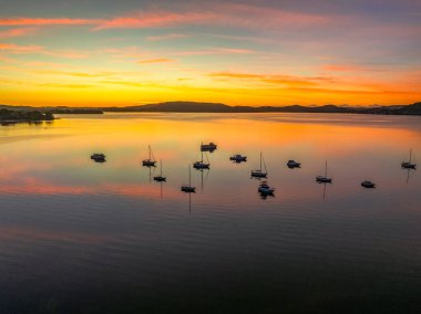 NSW, Avustralya 'nın merkez sahillerinde Brisbane Su ve Koolewong üzerinde bulutlu ve tekneli hava gündoğumu.