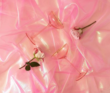 İki pembe gözlük ve parlak pembe kumaşta iki beyaz ve pembe gül. Parti davetiyesi ya da nişan kartı için şık bir konsept. Düz yatıyordu.