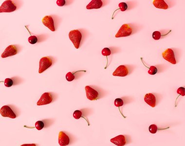 Pembe arka planda taze çilek ve kirazdan yapılmış bir bahar yaz duvar kağıdı. Üst görünüm.