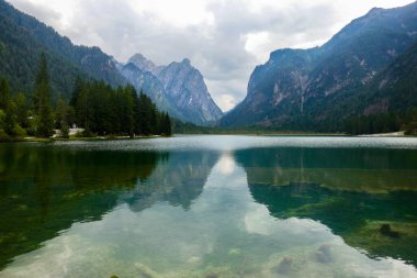 Meravigliosa vista panoramica del lago di Dobbiaco in una giornata nuvolosa d'estate, con i suoi idilliaci riflessi, Alpi italiane, Val Pusteria, Sud Tirolo, Italia. clipart