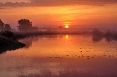Gölün üzerinde puslu bir şafak.