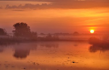 Gölün üzerinde puslu bir şafak.