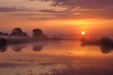 Gölün üzerinde puslu bir şafak.