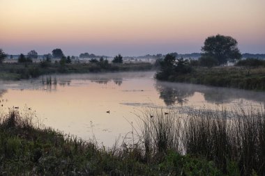 Gölün üzerinde puslu şafak.