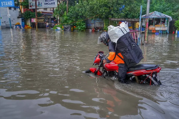 Çevrimiçi bir teslimatçı çocuk Hindistan, Kolkata 'da sular altında kalmış yoldan geçerken acı çekiyor..