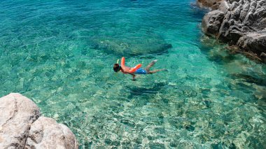 Boy with snorkel and mask explore underwater while swimming in crystal clear water of Aegean Sea, in Greece. Child have fun enjoy nature, swim and dive in turquoise sea pool on family beach vacation