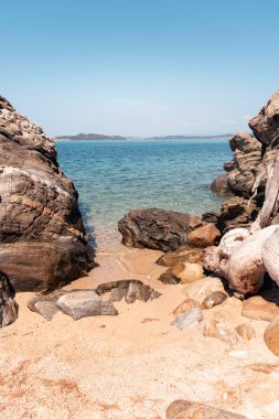 Vertical seascape nature background with rocks, golden sand, turquoise sea and clear blue sky in bright sunny summer day. Beach in Greece, Halkidiki, Athos peninsula. Travel destination