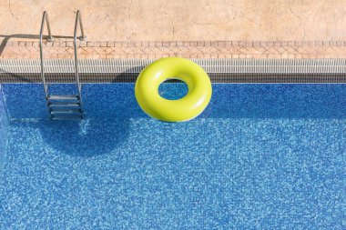 Mavi havuz suyunda yüzen renkli bir halka. Fotokopi alanı olan eğlenceli bir yaz ortamı. Serinletici, kaçış, yaz tatillerinde aktif rahatlama.