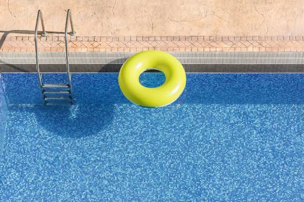 Mavi havuz suyunda yüzen renkli bir halka. Fotokopi alanı olan eğlenceli bir yaz ortamı. Serinletici, kaçış, yaz tatillerinde aktif rahatlama.